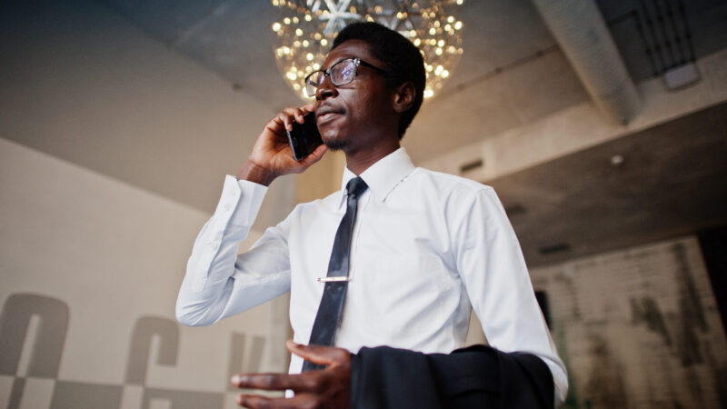 Business african american man wear on white shirt, tie and glasses at office speaking on mobile phone.