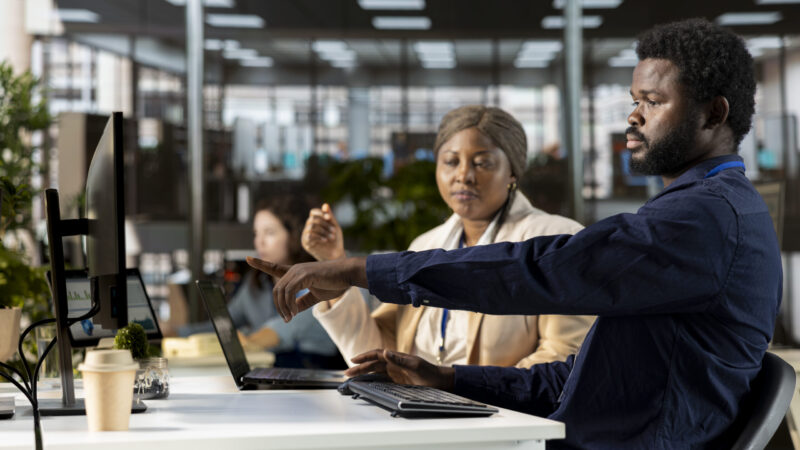 Manager reviews company infographics with a team member in a corporate office, making important organizational decisions to support global expansion. Discuss resource allocation.