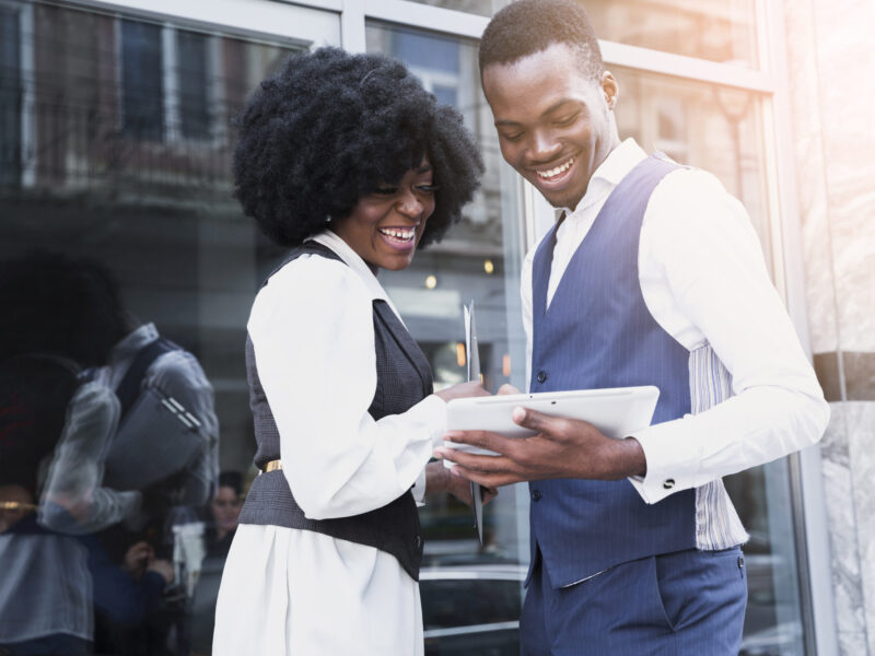 portrait-smiling-young-african-businessman-businesswoman-looking-digital-tablet